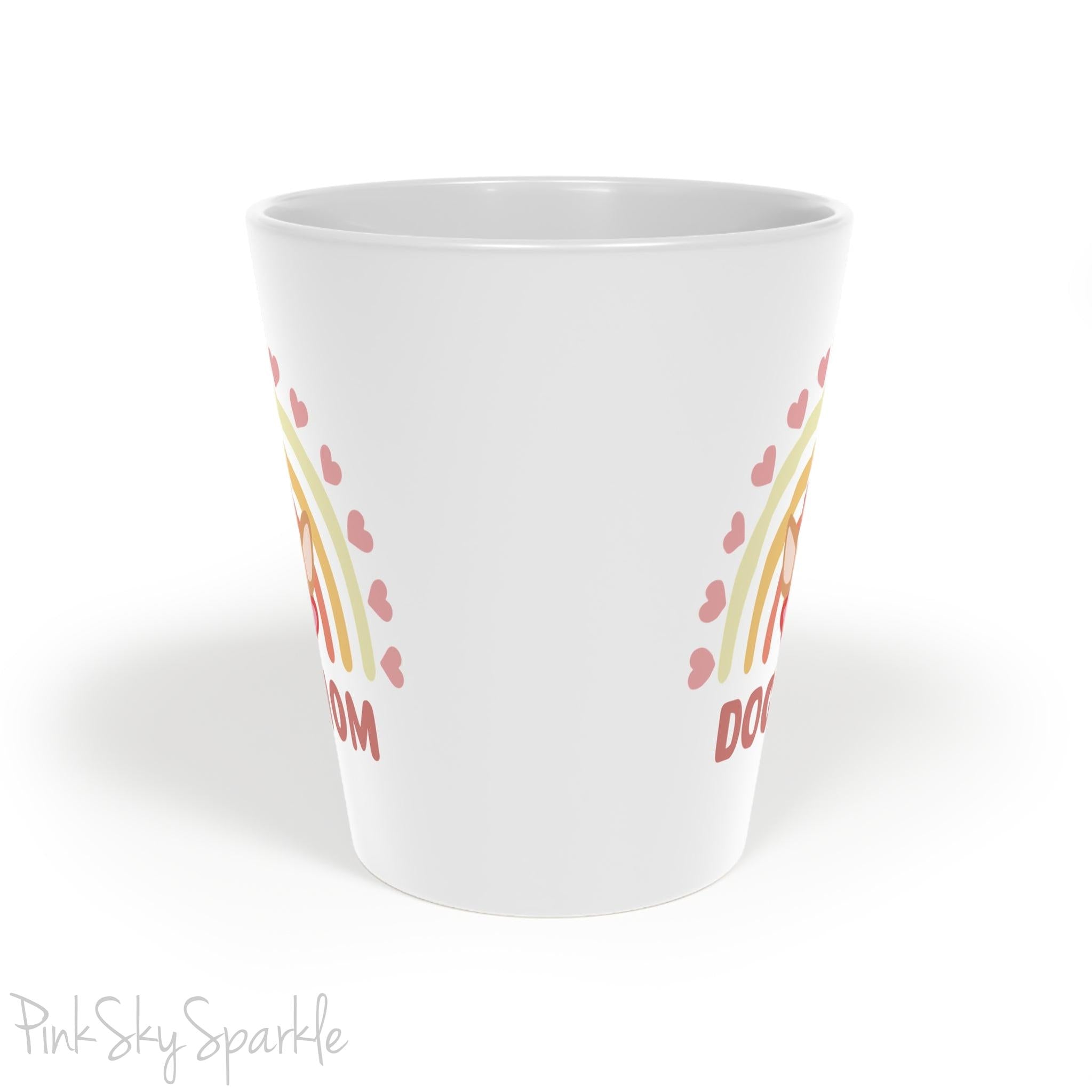 Dog Mom, Rainbow & Hearts Latte Mug. A white 12oz latte mug featuring a boho style rainbow with hearts and a chihuahua wearing heart shaped glasses in the center and the words Dog Mom written in all caps below it.