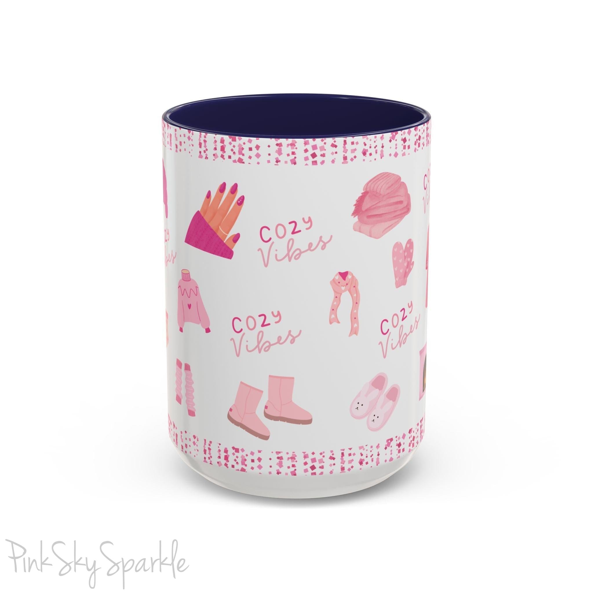 Pink Cozy Vibes Mug - Perfect for coffee, tea, or hot cocoa lovers! This ceramic mug features 'cozy vibes' in a pink font, surrounded by cute illustrations of pink cozy items such as slippers, mittens, blankets and candles. Ideal for creating a warm, cozy atmosphere, this pink-handled mug (also available in light blue, black and navy) makes a great gift for anyone who loves comfort, style and the color pink.