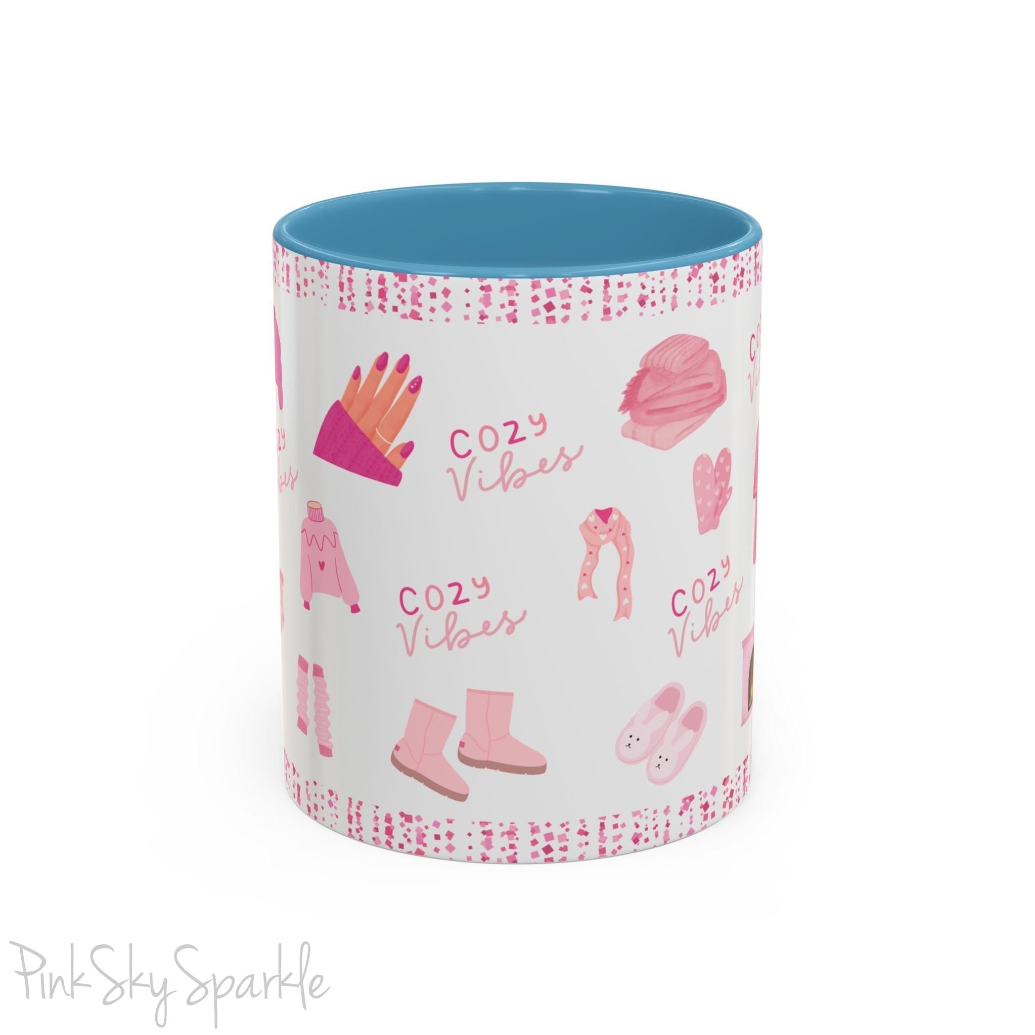 Pink Cozy Vibes Mug - Perfect for coffee, tea, or hot cocoa lovers! This ceramic mug features 'cozy vibes' in a pink font, surrounded by cute illustrations of pink cozy items such as slippers, mittens, blankets and candles. Ideal for creating a warm, cozy atmosphere, this pink-handled mug (also available in light blue, black and navy) makes a great gift for anyone who loves comfort, style and the color pink.