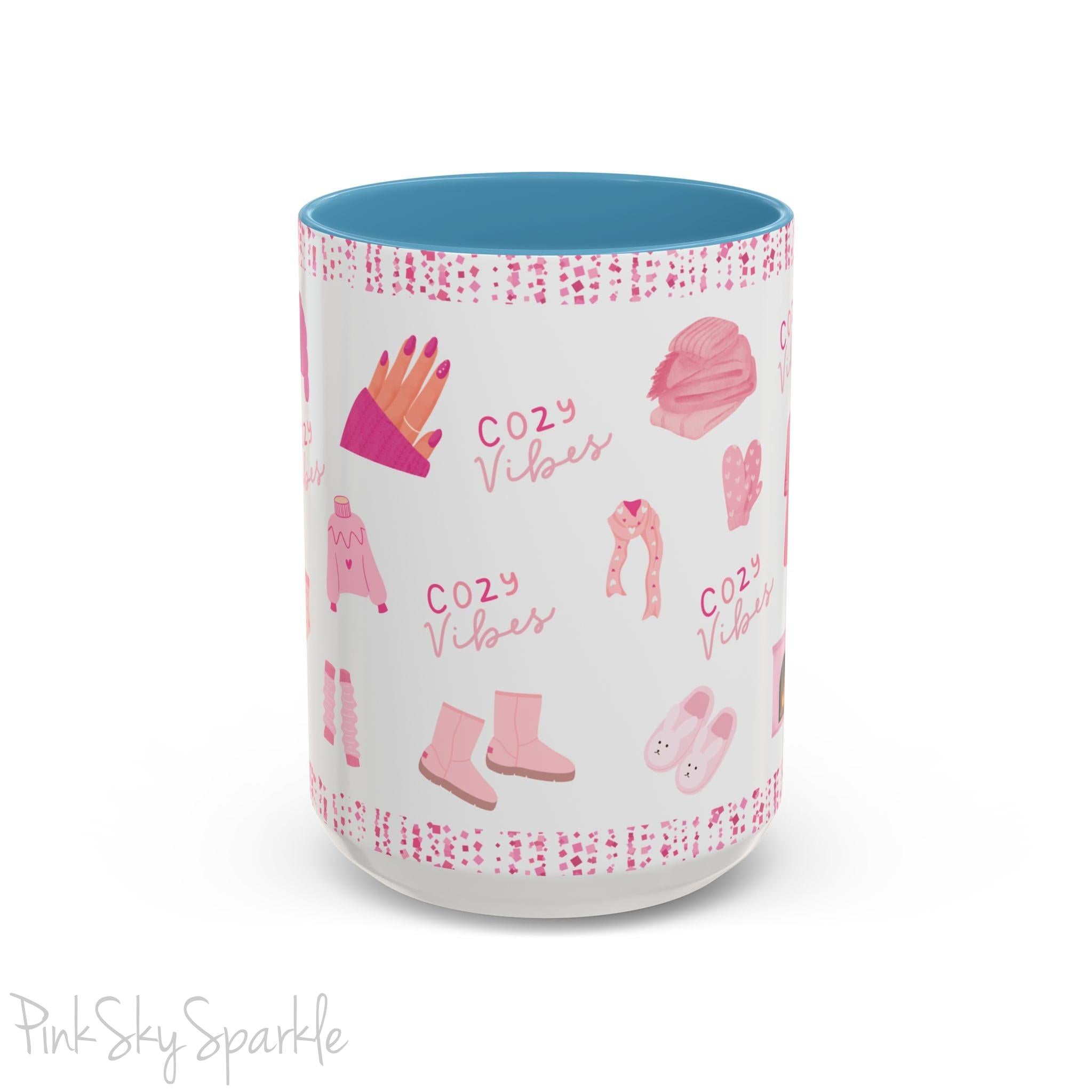 Pink Cozy Vibes Mug - Perfect for coffee, tea, or hot cocoa lovers! This ceramic mug features 'cozy vibes' in a pink font, surrounded by cute illustrations of pink cozy items such as slippers, mittens, blankets and candles. Ideal for creating a warm, cozy atmosphere, this pink-handled mug (also available in light blue, black and navy) makes a great gift for anyone who loves comfort, style and the color pink.