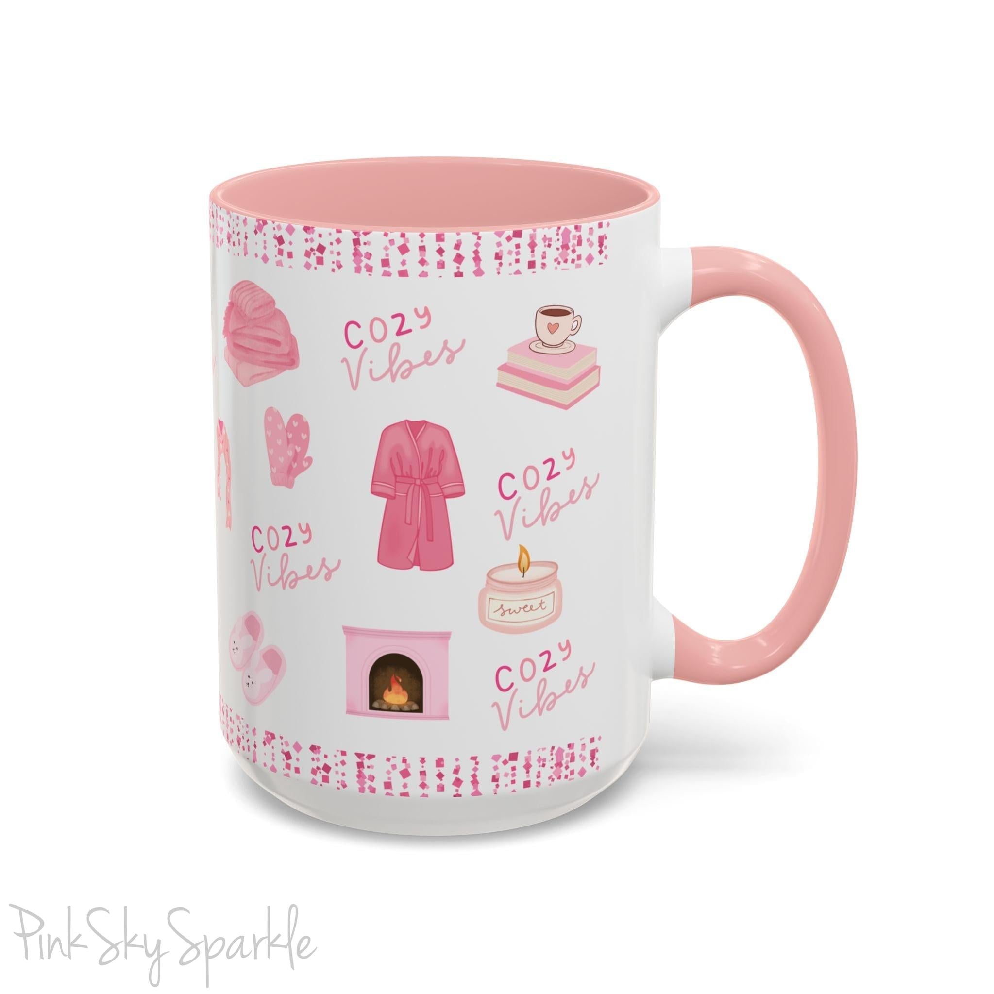 Pink Cozy Vibes Mug - Perfect for coffee, tea, or hot cocoa lovers! This ceramic mug features 'cozy vibes' in a pink font, surrounded by cute illustrations of pink cozy items such as slippers, mittens, blankets and candles. Ideal for creating a warm, cozy atmosphere, this pink-handled mug (also available in light blue, black and navy) makes a great gift for anyone who loves comfort, style and the color pink.