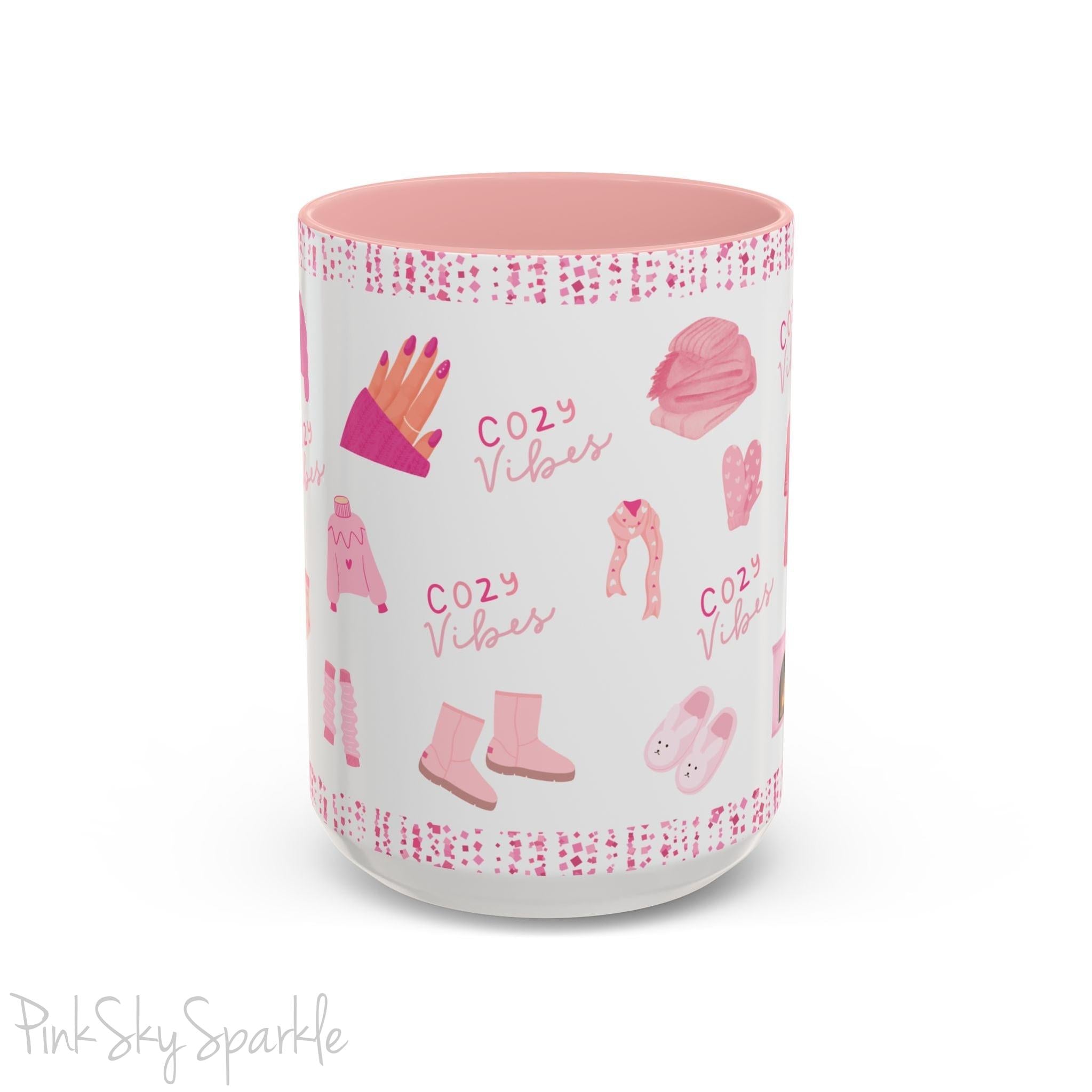 Pink Cozy Vibes Mug - Perfect for coffee, tea, or hot cocoa lovers! This ceramic mug features 'cozy vibes' in a pink font, surrounded by cute illustrations of pink cozy items such as slippers, mittens, blankets and candles. Ideal for creating a warm, cozy atmosphere, this pink-handled mug (also available in light blue, black and navy) makes a great gift for anyone who loves comfort, style and the color pink.