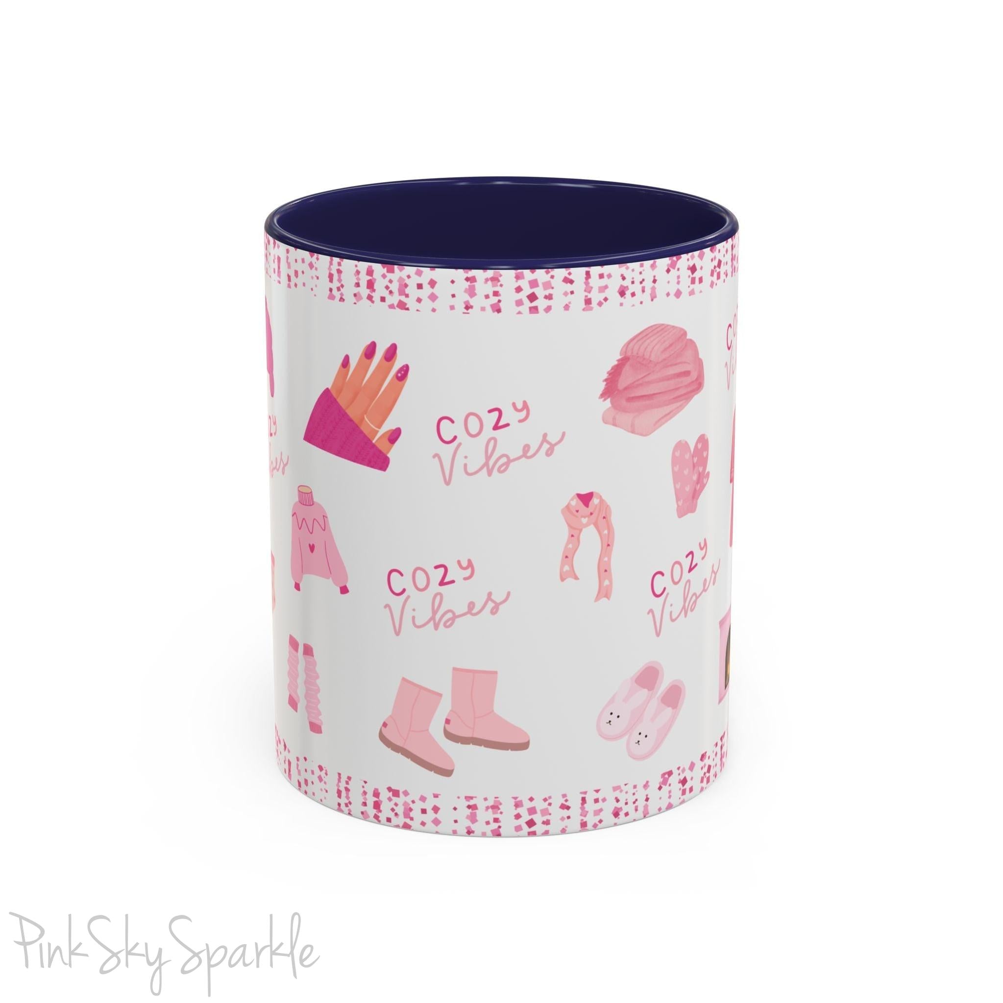 Pink Cozy Vibes Mug - Perfect for coffee, tea, or hot cocoa lovers! This ceramic mug features 'cozy vibes' in a pink font, surrounded by cute illustrations of pink cozy items such as slippers, mittens, blankets and candles. Ideal for creating a warm, cozy atmosphere, this pink-handled mug (also available in light blue, black and navy) makes a great gift for anyone who loves comfort, style and the color pink.