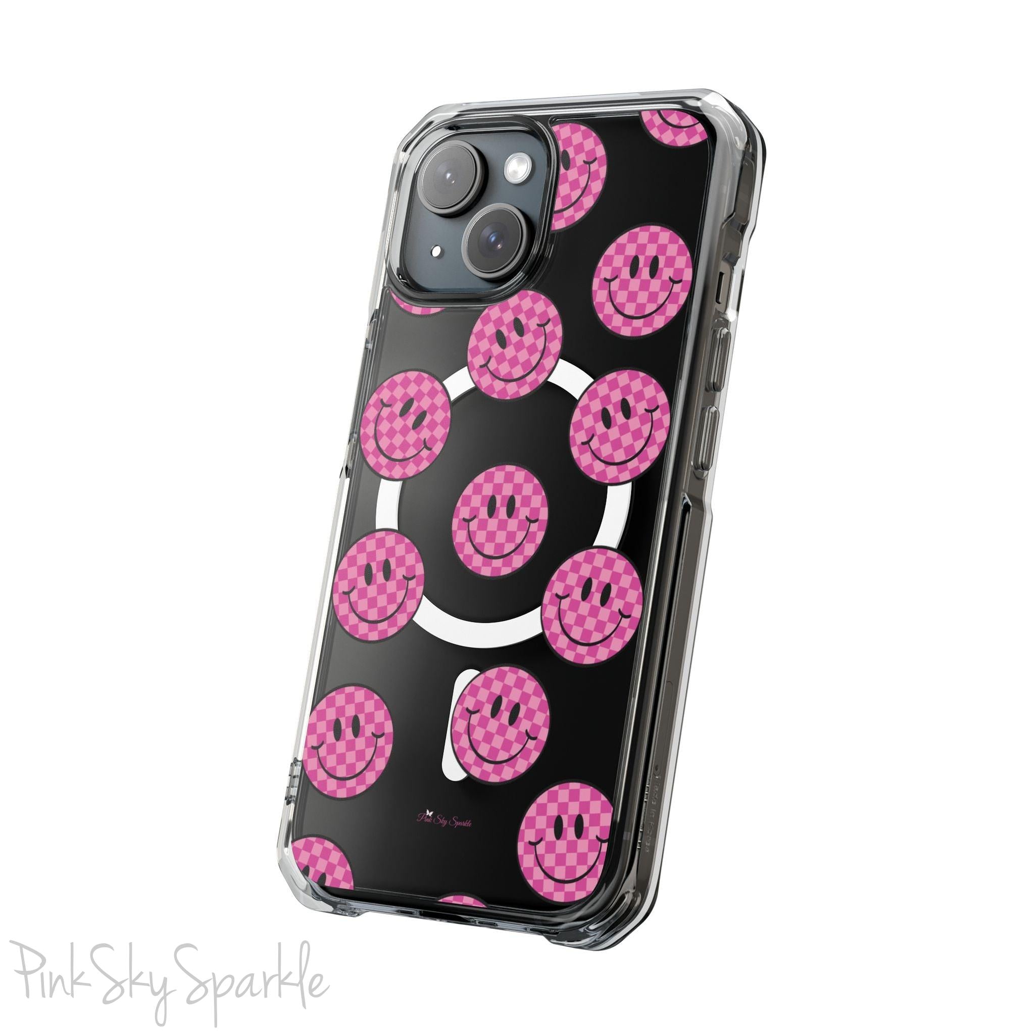 Clear magnetic phone case featuring pink checkered smiley faces on a transparent background, designed for MagSafe® compatibility with air-cushioned bumper corners.