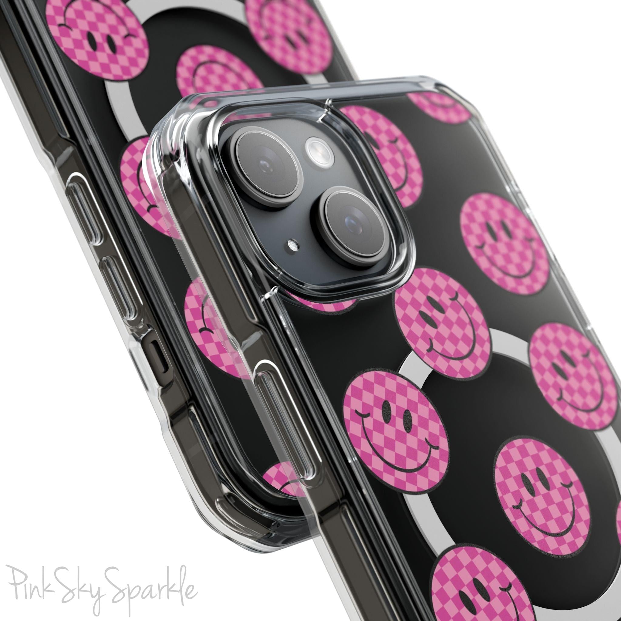Clear magnetic phone case featuring pink checkered smiley faces on a transparent background, designed for MagSafe® compatibility with air-cushioned bumper corners.