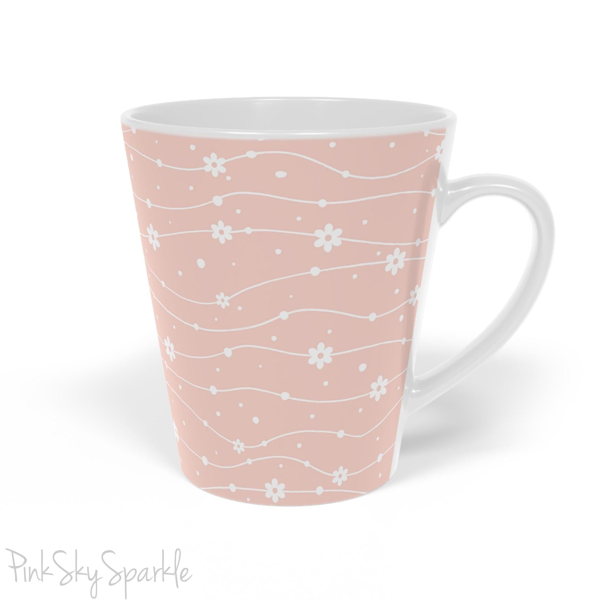 Experience the joy of sipping your favourite latte from our beautiful Wavy Daisy Latte Mug. Crafted from durable materials, this 12oz mug is perfect for everyday use and makes a lovely gift for any coffee or tea lover. Featuring a soft pink background on a white mug, with a wavy line pattern with white daisy flowers and dots throughout.