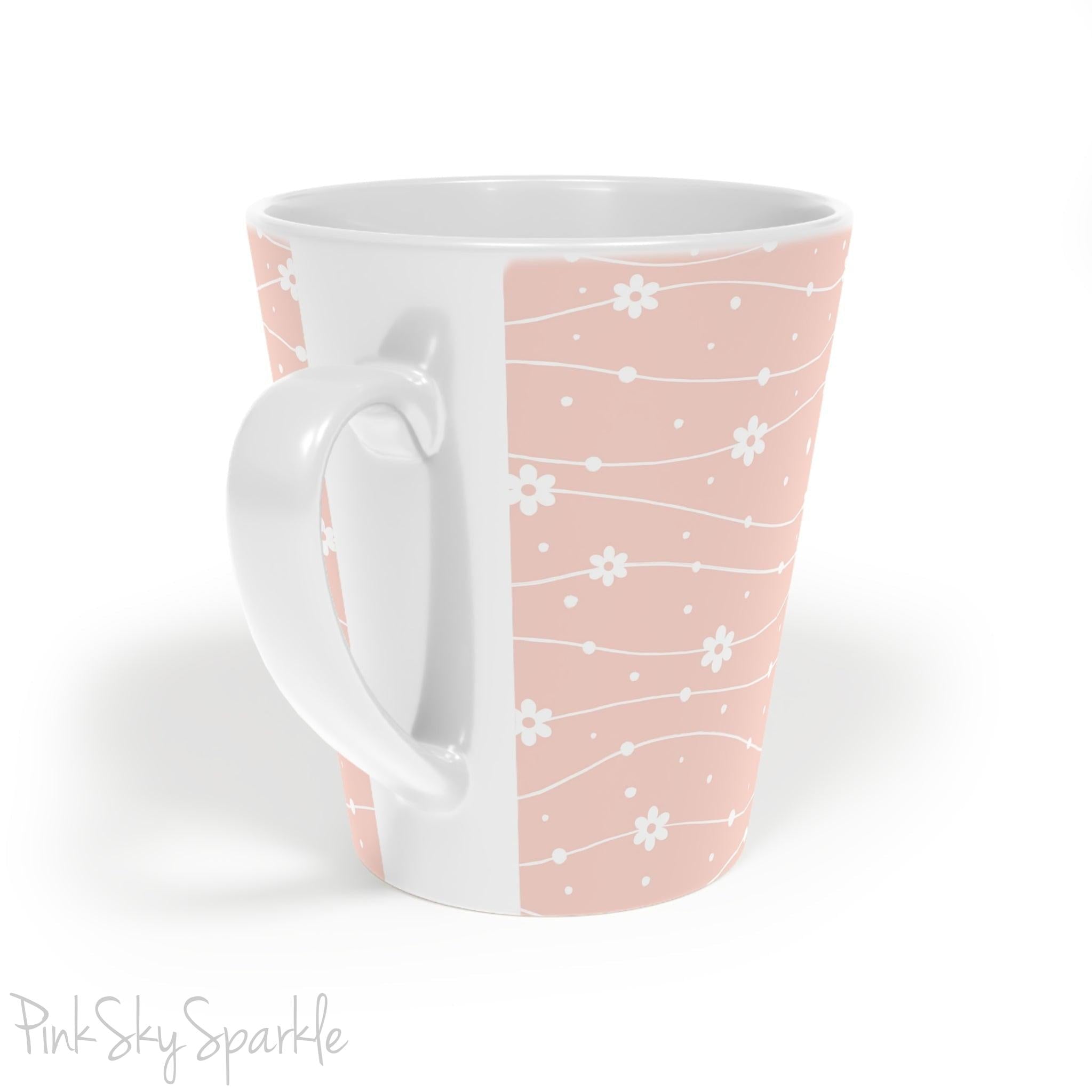 Experience the joy of sipping your favourite latte from our beautiful Wavy Daisy Latte Mug. Crafted from durable materials, this 12oz mug is perfect for everyday use and makes a lovely gift for any coffee or tea lover. Featuring a soft pink background on a white mug, with a wavy line pattern with white daisy flowers and dots throughout.