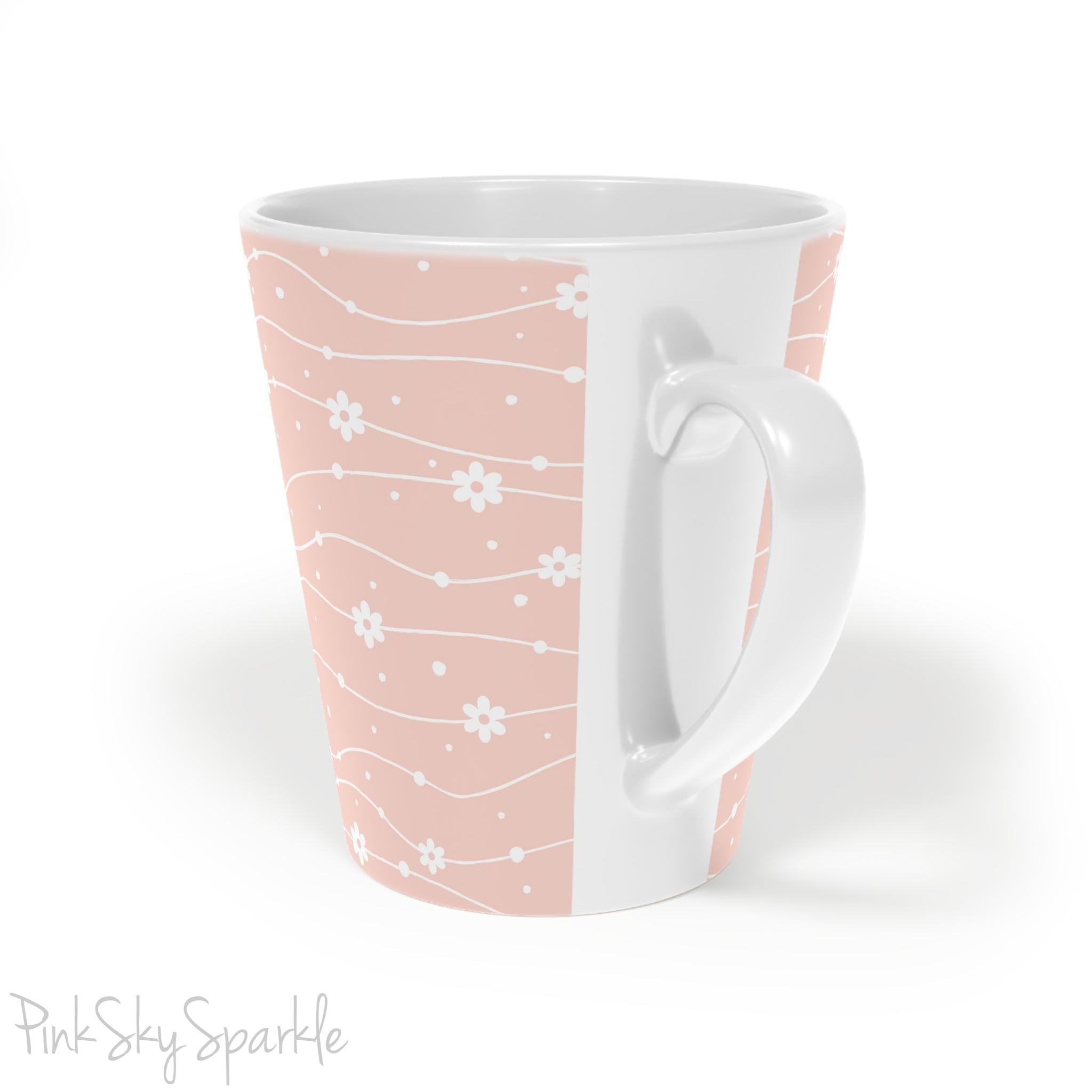Experience the joy of sipping your favourite latte from our beautiful Wavy Daisy Latte Mug. Crafted from durable materials, this 12oz mug is perfect for everyday use and makes a lovely gift for any coffee or tea lover. Featuring a soft pink background on a white mug, with a wavy line pattern with white daisy flowers and dots throughout.