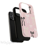 Pink magnetic iPhone case featuring an elegant bow pattern with black, white, and cream bows, designed for MagSafe® compatibility and premium protection.