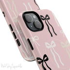Pink magnetic iPhone case featuring an elegant bow pattern with black, white, and cream bows, designed for MagSafe® compatibility and premium protection.