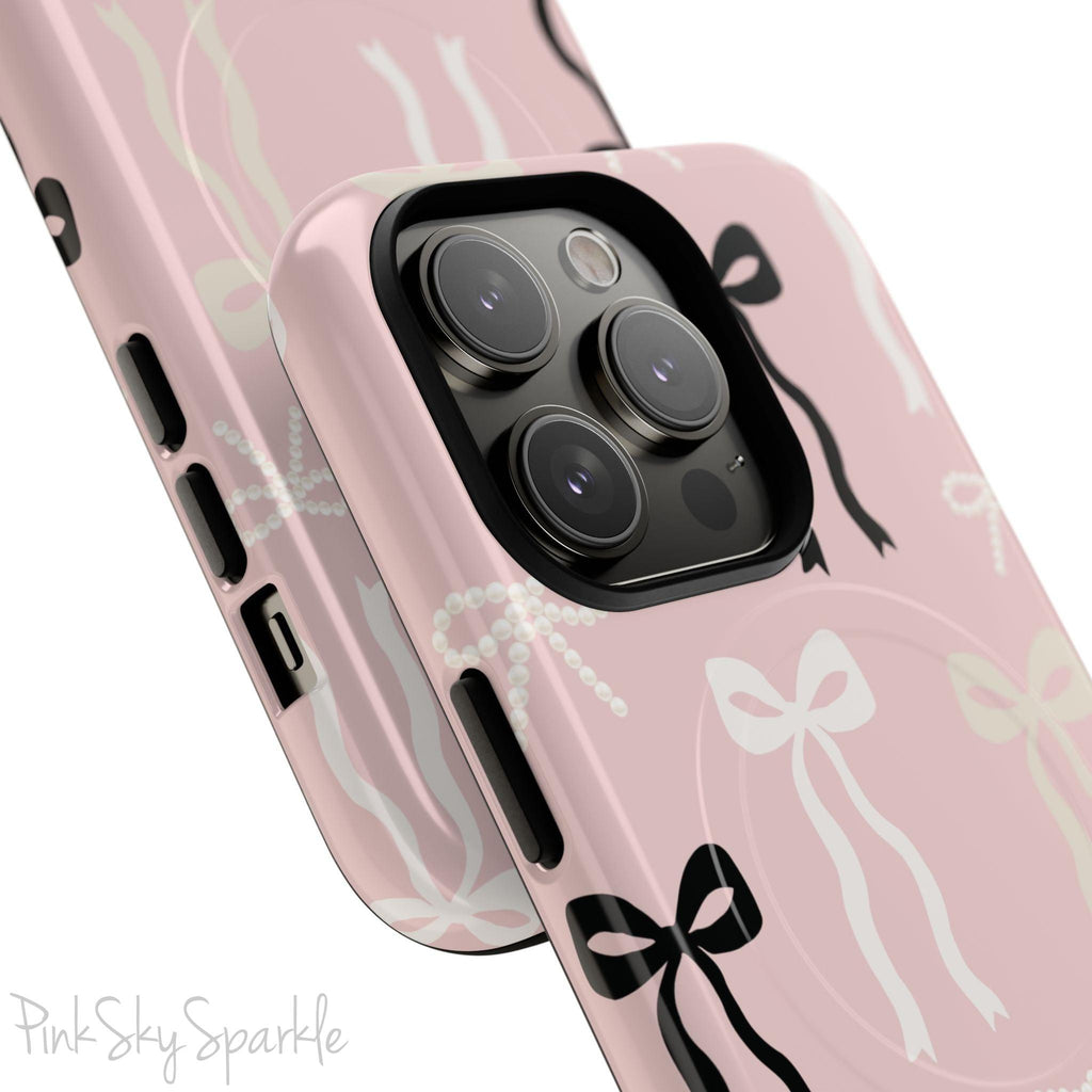 Pink magnetic iPhone case featuring an elegant bow pattern with black, white, and cream bows, designed for MagSafe® compatibility and premium protection.