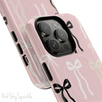 Pink magnetic iPhone case featuring an elegant bow pattern with black, white, and cream bows, designed for MagSafe® compatibility and premium protection.