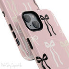 Pink magnetic iPhone case featuring an elegant bow pattern with black, white, and cream bows, designed for MagSafe® compatibility and premium protection.