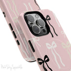 Pink magnetic iPhone case featuring an elegant bow pattern with black, white, and cream bows, designed for MagSafe® compatibility and premium protection.