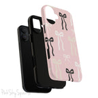 Pink magnetic iPhone case featuring an elegant bow pattern with black, white, and cream bows, designed for MagSafe® compatibility and premium protection.
