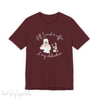 "All I need is coffee and my chihuahua" T-shirt. Featuring a graphic of a woman wearing a robe and hair towel, wearing black sunglasses drinking a coffee next to a chihuahua wearing black sunglasses.
