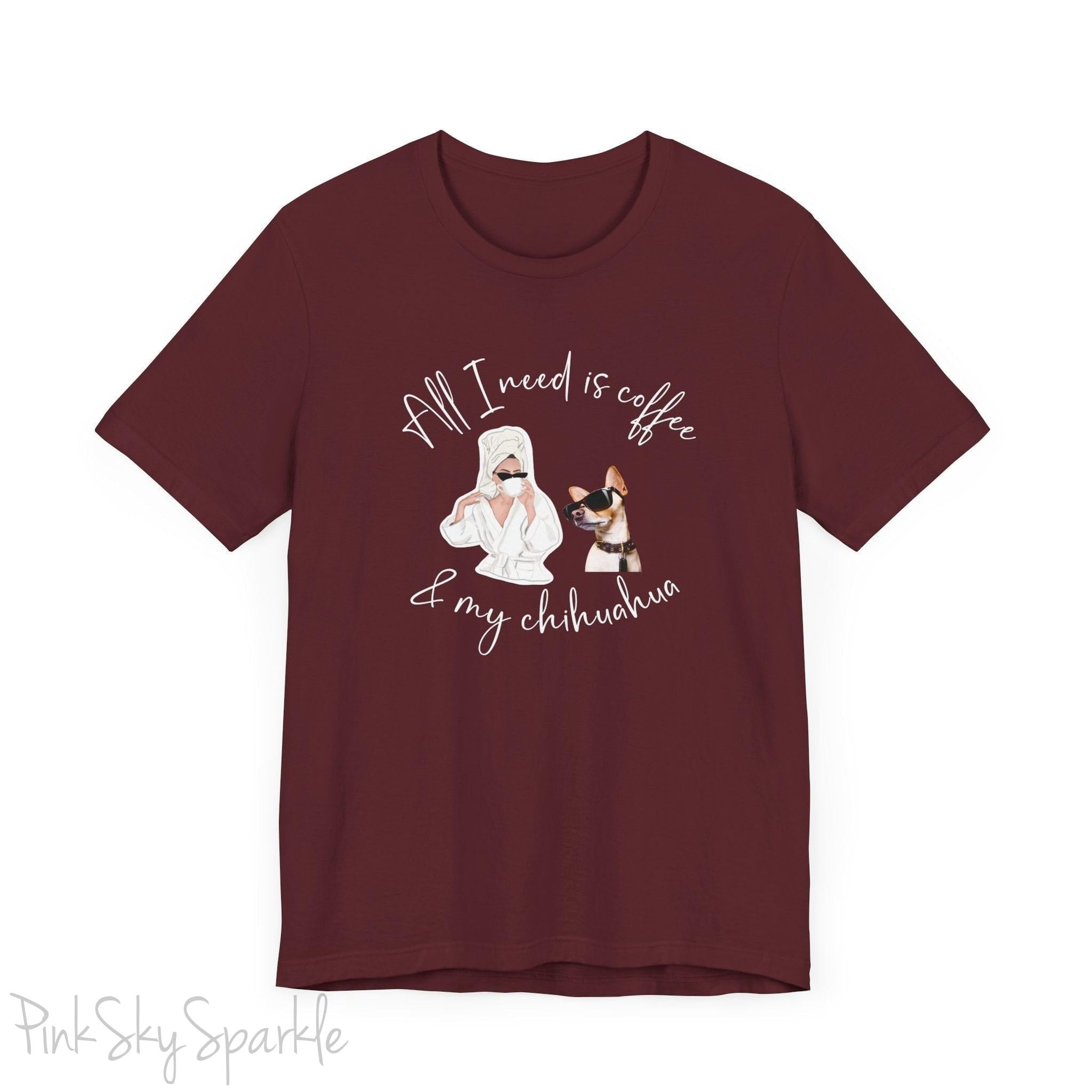 "All I need is coffee and my chihuahua" T-shirt. Featuring a graphic of a woman wearing a robe and hair towel, wearing black sunglasses drinking a coffee next to a chihuahua wearing black sunglasses.