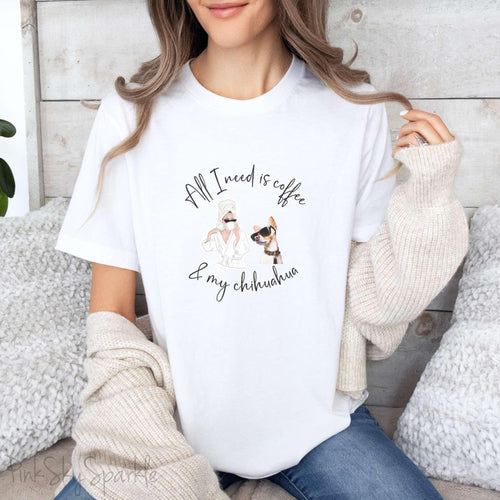 "All I need is coffee and my chihuahua" T-shirt. Featuring a graphic of a woman wearing a robe and hair towel, wearing black sunglasses drinking a coffee next to a chihuahua wearing black sunglasses.