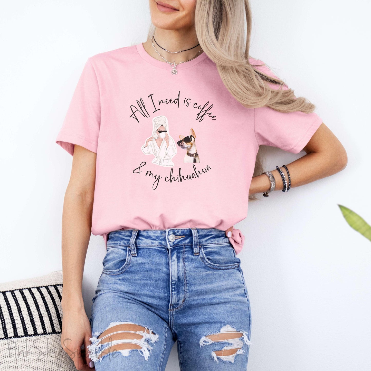 "All I need is coffee and my chihuahua" T-shirt. Featuring a graphic of a woman wearing a robe and hair towel, wearing black sunglasses drinking a coffee next to a chihuahua wearing black sunglasses.