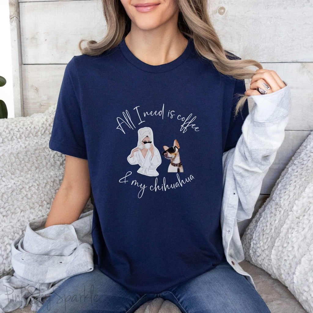 "All I need is coffee and my chihuahua" T-shirt. Featuring a graphic of a woman wearing a robe and hair towel, wearing black sunglasses drinking a coffee next to a chihuahua wearing black sunglasses.