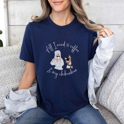 "All I need is coffee and my chihuahua" T-shirt. Featuring a graphic of a woman wearing a robe and hair towel, wearing black sunglasses drinking a coffee next to a chihuahua wearing black sunglasses.