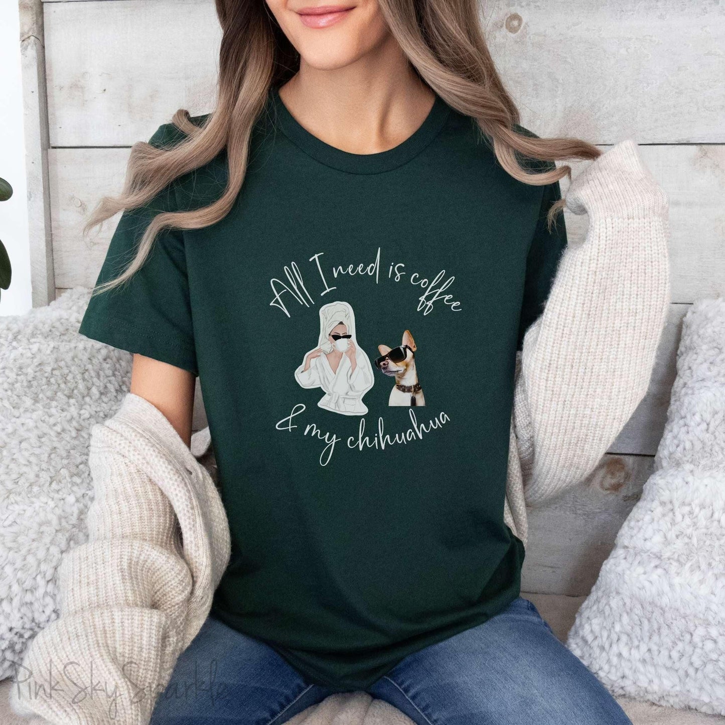 "All I need is coffee and my chihuahua" T-shirt. Featuring a graphic of a woman wearing a robe and hair towel, wearing black sunglasses drinking a coffee next to a chihuahua wearing black sunglasses.