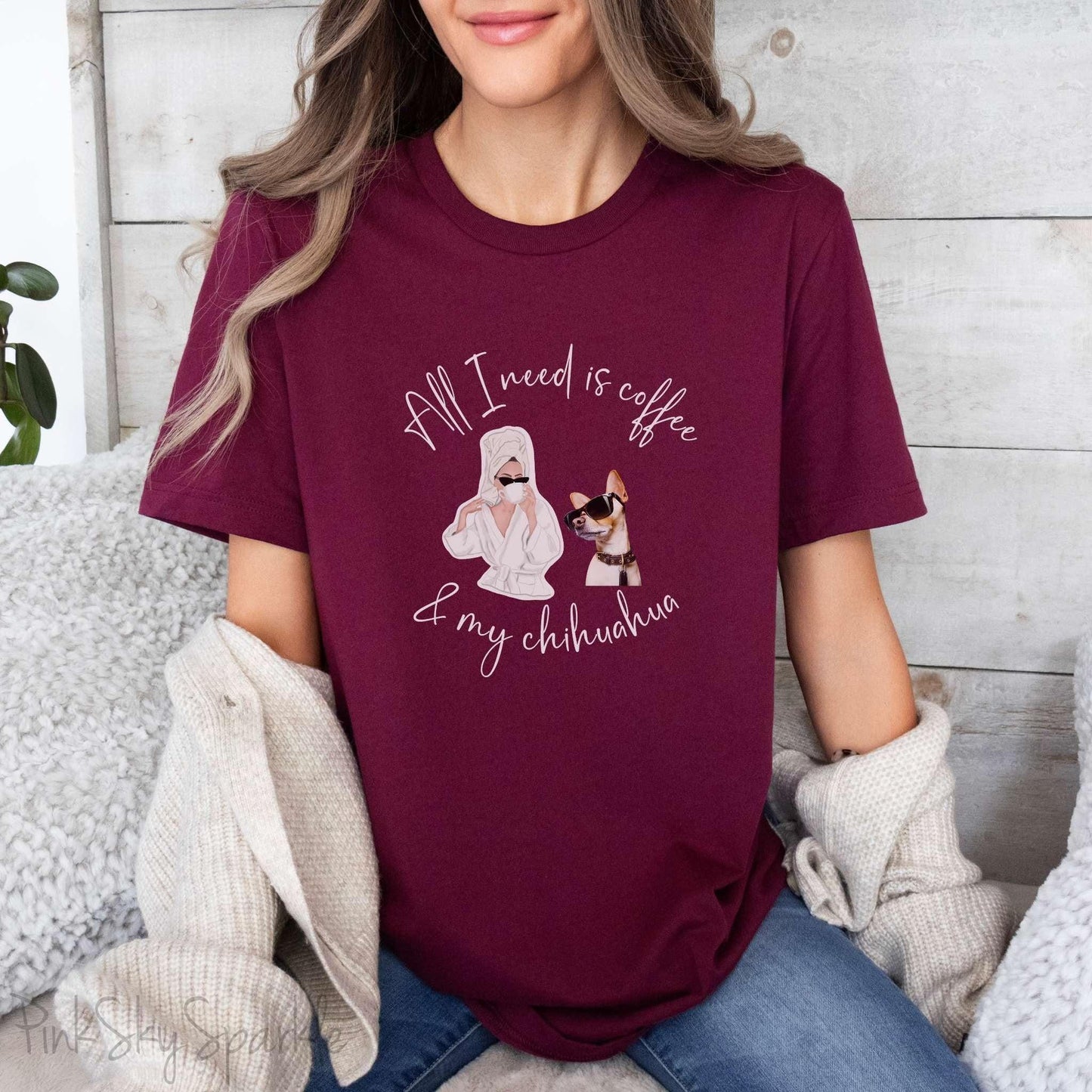 "All I need is coffee and my chihuahua" T-shirt. Featuring a graphic of a woman wearing a robe and hair towel, wearing black sunglasses drinking a coffee next to a chihuahua wearing black sunglasses.