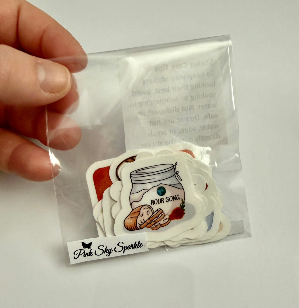 Packaged stickers with illustrations held by a hand on a white background