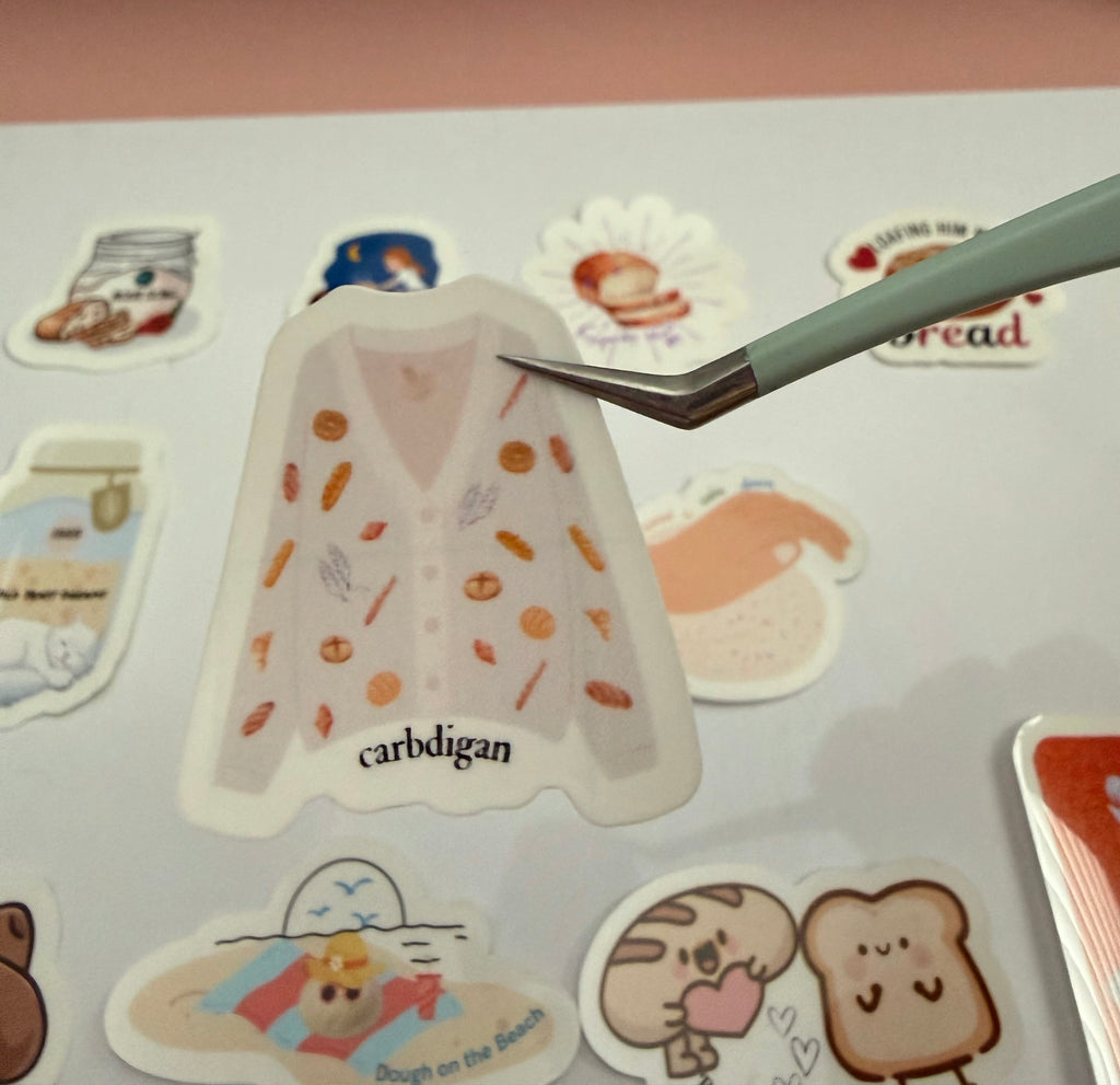 Sticker of a cardigan with bread design on it with the pun 'carbdigan'.
