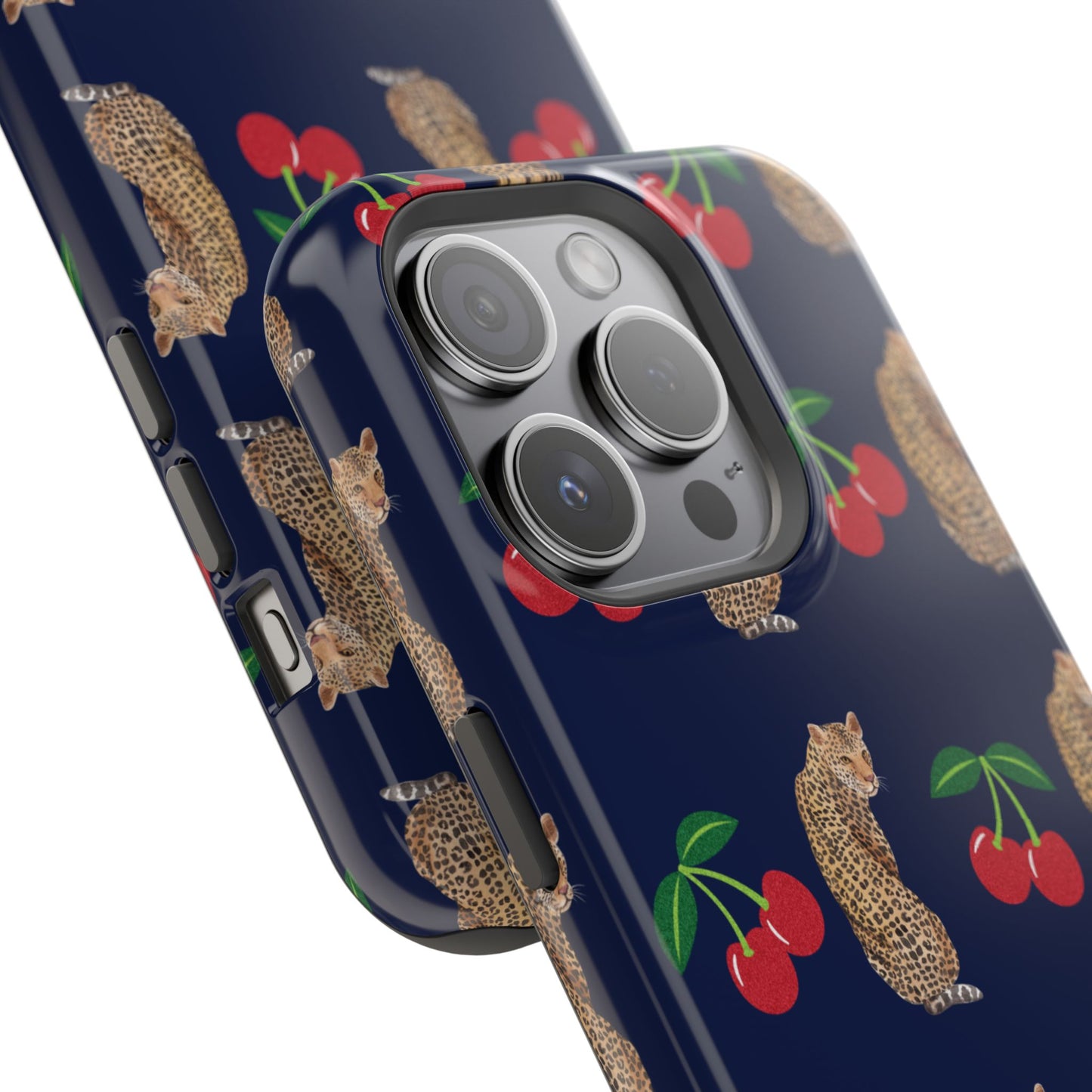 A stylish magnetic iPhone case featuring a unique pattern of leopards and bright red cherries on a dark navy blue background, blending bold and playful elements.