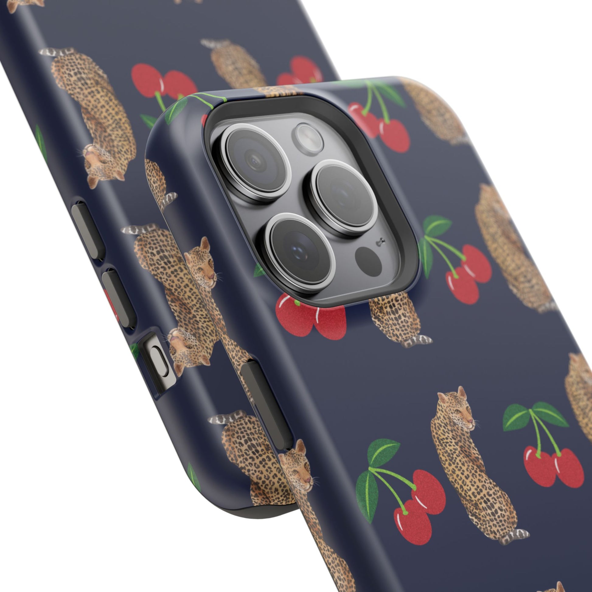 A stylish magnetic iPhone case featuring a unique pattern of leopards and bright red cherries on a dark navy blue background, blending bold and playful elements.