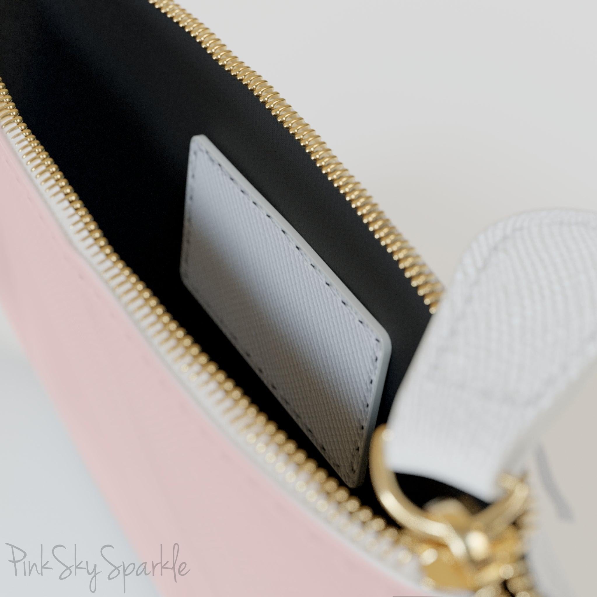 Close-up of gold zipper and white wrist strap on the pink mini clutch bag.