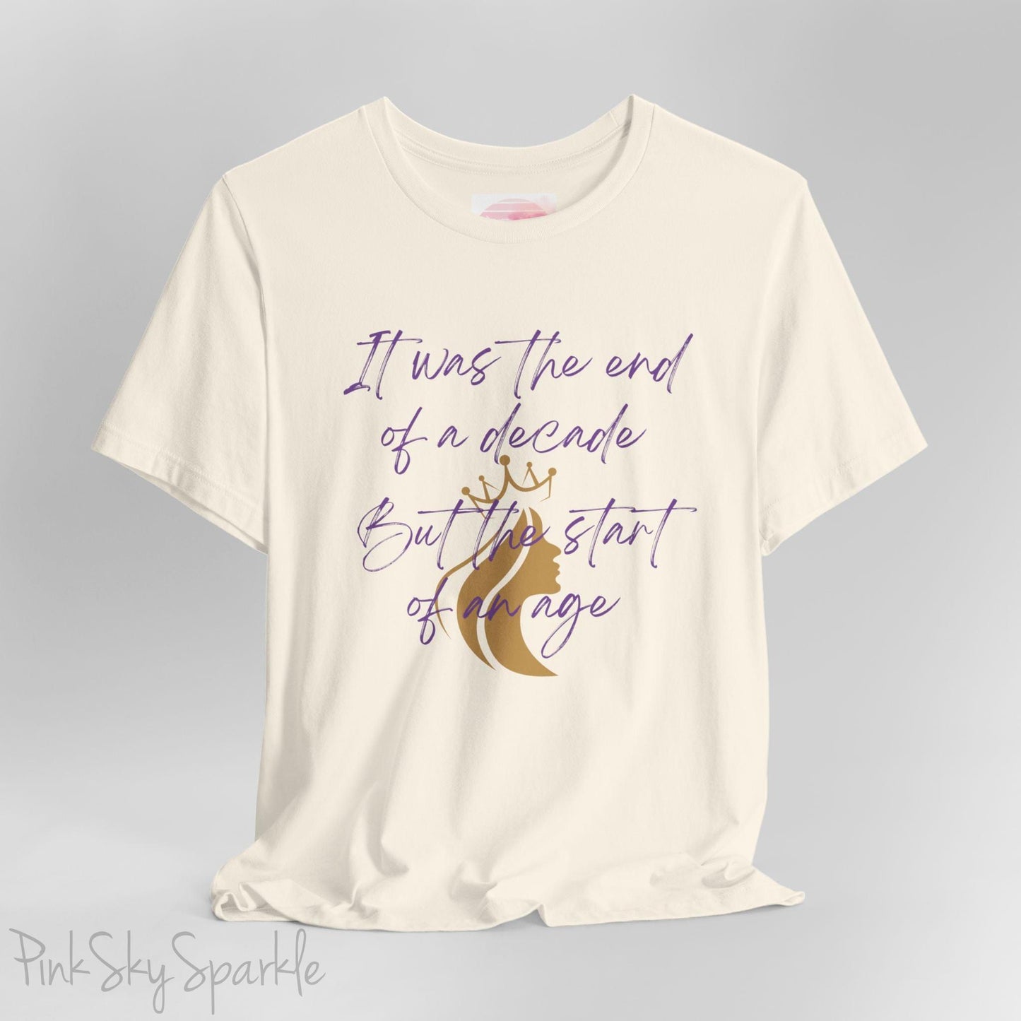 Embrace the excitement of a new era with our End of a Decade, Start of an Age T-shirt, inspired by Taylor Swift's iconic lyrics. Featuring the words It was the end of a decade, But the start of an age in a purple marker script font with a gold silhouette of a woman wearing a crown.