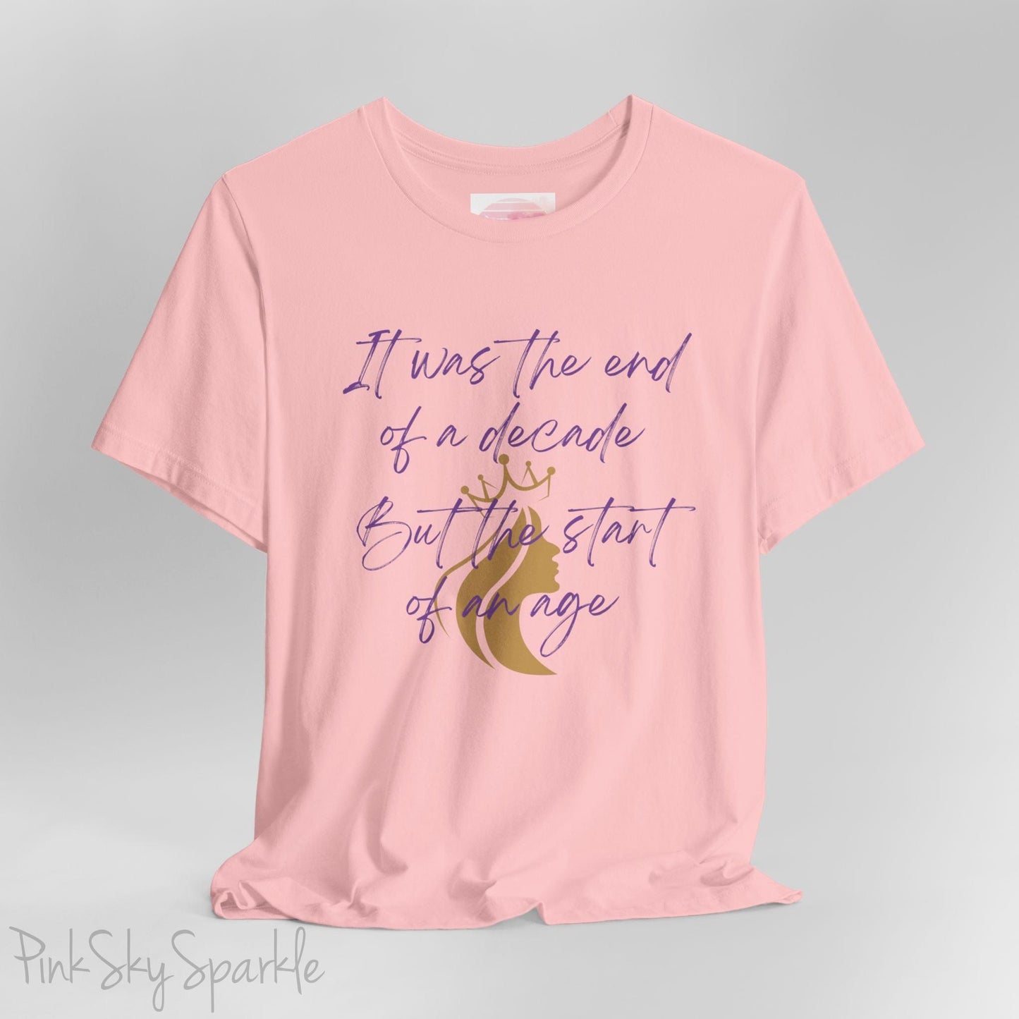Embrace the excitement of a new era with our End of a Decade, Start of an Age T-shirt, inspired by Taylor Swift's iconic lyrics. Featuring the words It was the end of a decade, But the start of an age in a purple marker script font with a gold silhouette of a woman wearing a crown.