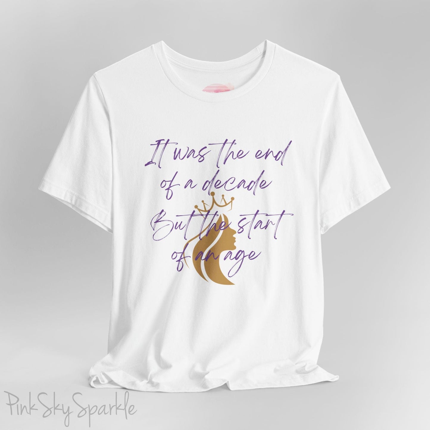 Embrace the excitement of a new era with our End of a Decade, Start of an Age T-shirt, inspired by Taylor Swift's iconic lyrics. Featuring the words It was the end of a decade, But the start of an age in a purple marker script font with a gold silhouette of a woman wearing a crown.