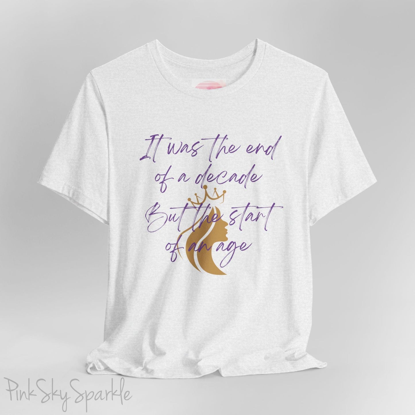 Embrace the excitement of a new era with our End of a Decade, Start of an Age T-shirt, inspired by Taylor Swift's iconic lyrics. Featuring the words It was the end of a decade, But the start of an age in a purple marker script font with a gold silhouette of a woman wearing a crown.