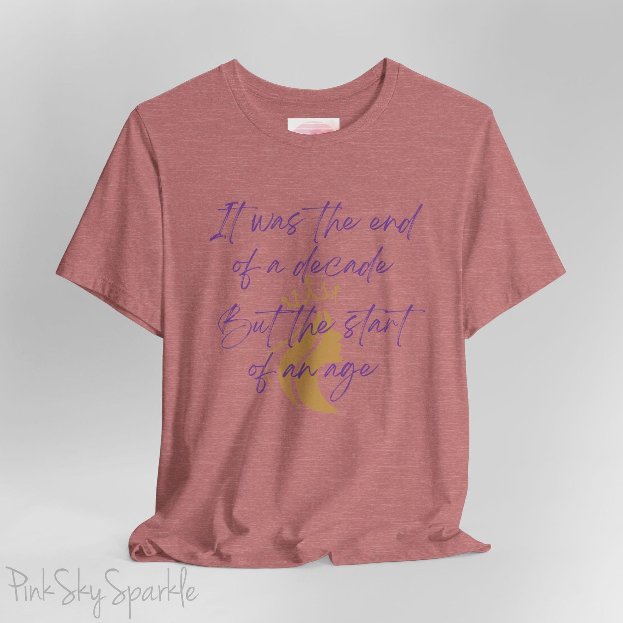 Embrace the excitement of a new era with our End of a Decade, Start of an Age T-shirt, inspired by Taylor Swift's iconic lyrics. Featuring the words It was the end of a decade, But the start of an age in a purple marker script font with a gold silhouette of a woman wearing a crown.