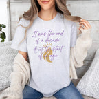 Embrace the excitement of a new era with our End of a Decade, Start of an Age T-shirt, inspired by Taylor Swift's iconic lyrics. Featuring the words It was the end of a decade, But the start of an age in a purple marker script font with a gold silhouette of a woman wearing a crown.