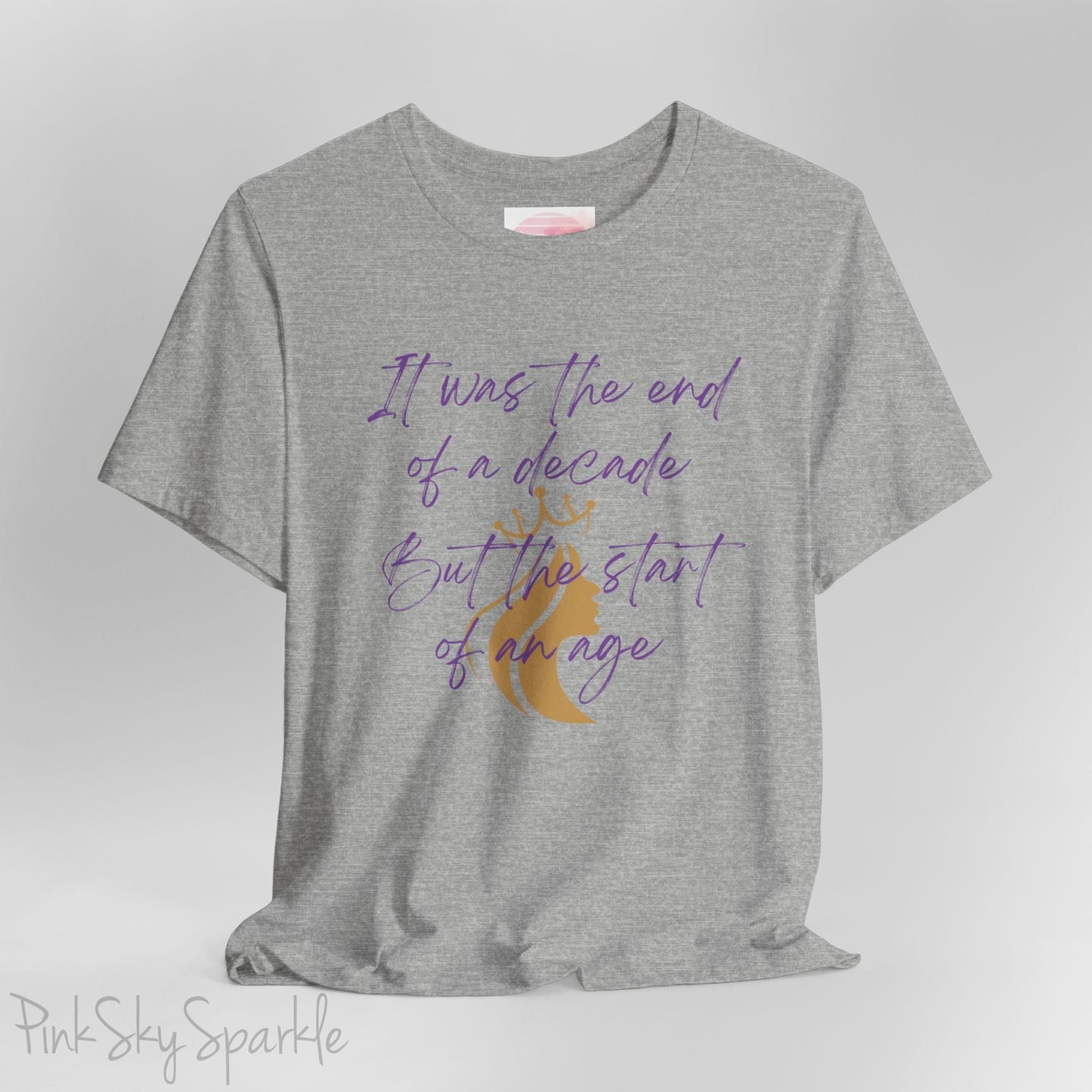 Embrace the excitement of a new era with our End of a Decade, Start of an Age T-shirt, inspired by Taylor Swift's iconic lyrics. Featuring the words It was the end of a decade, But the start of an age in a purple marker script font with a gold silhouette of a woman wearing a crown.