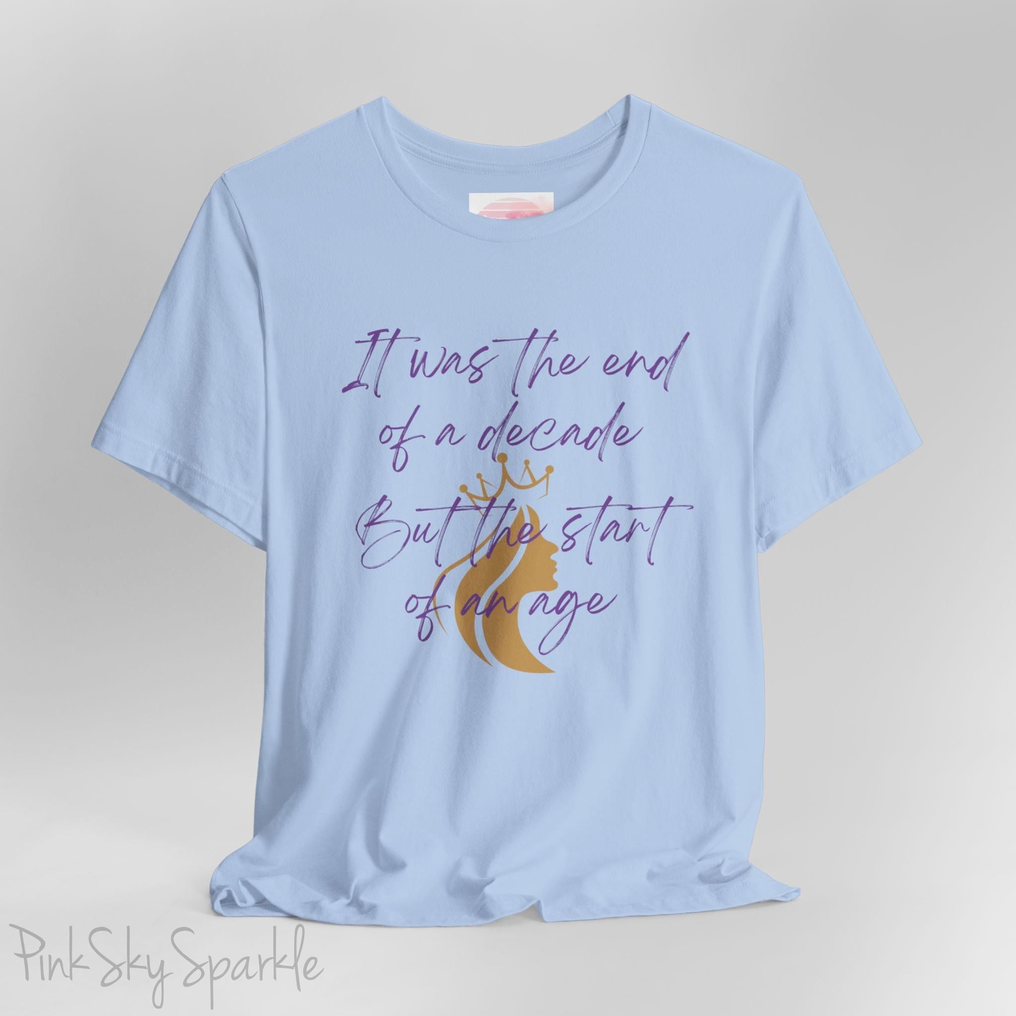 Embrace the excitement of a new era with our End of a Decade, Start of an Age T-shirt, inspired by Taylor Swift's iconic lyrics. Featuring the words It was the end of a decade, But the start of an age in a purple marker script font with a gold silhouette of a woman wearing a crown.
