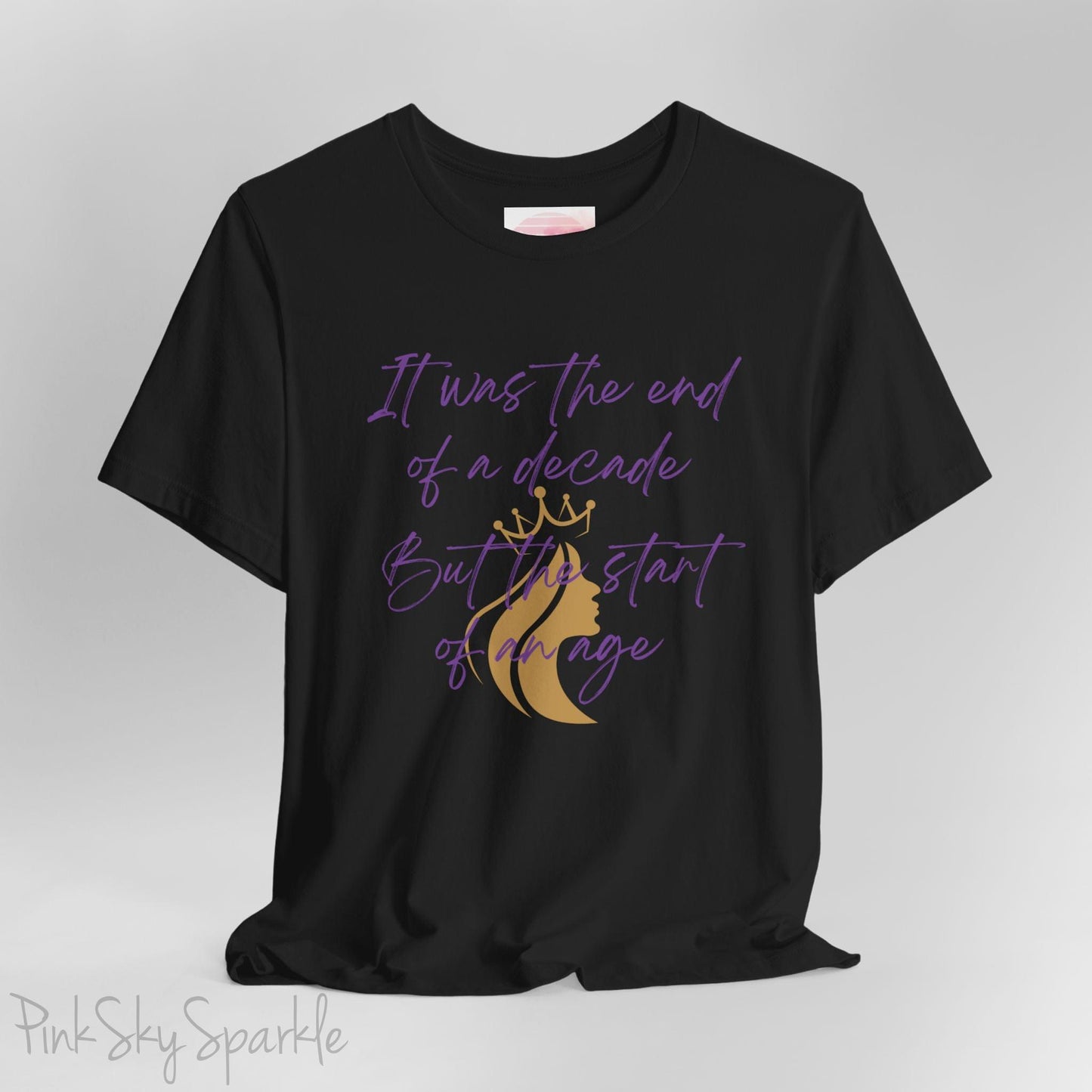 Embrace the excitement of a new era with our End of a Decade, Start of an Age T-shirt, inspired by Taylor Swift's iconic lyrics. Featuring the words It was the end of a decade, But the start of an age in a purple marker script font with a gold silhouette of a woman wearing a crown.