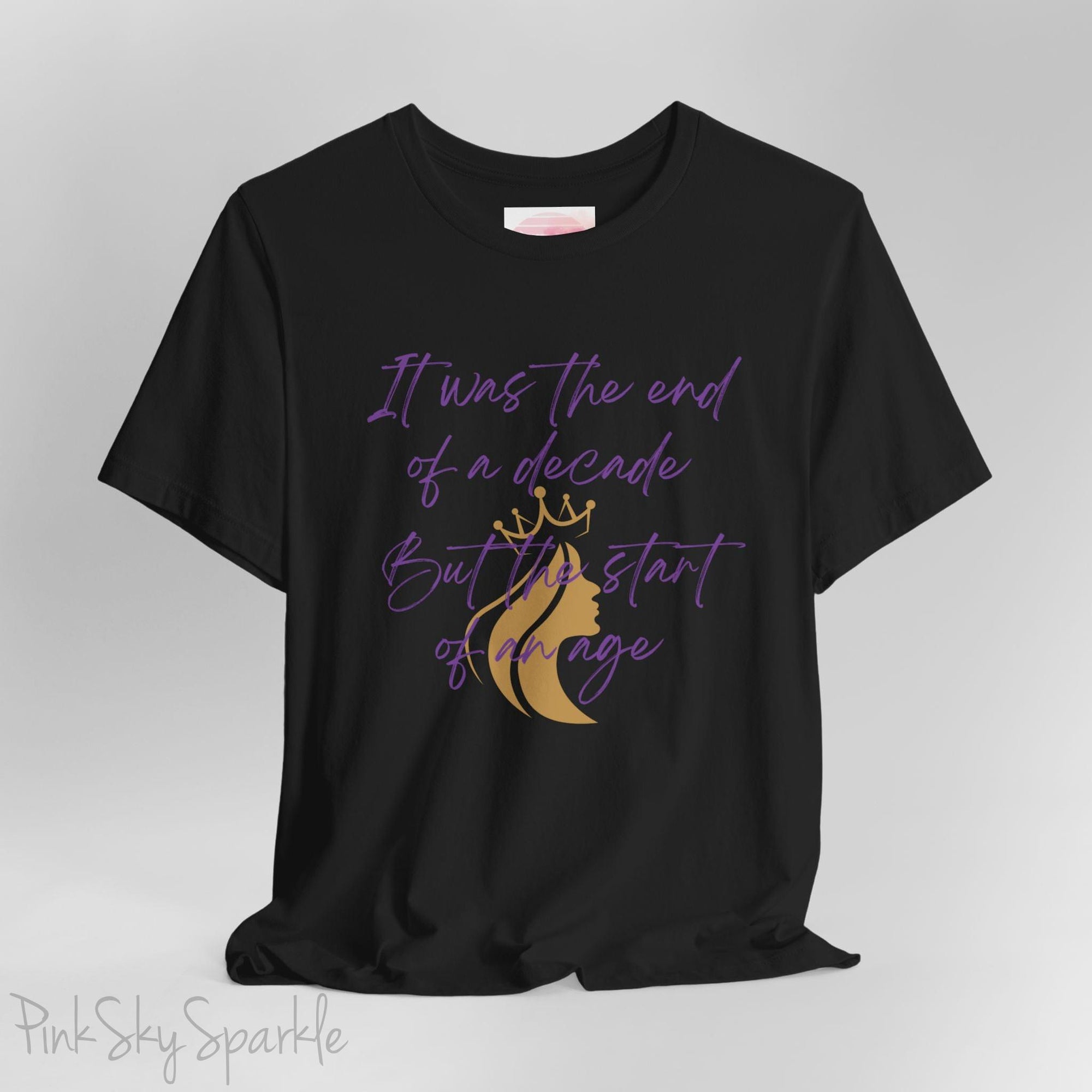 Embrace the excitement of a new era with our End of a Decade, Start of an Age T-shirt, inspired by Taylor Swift's iconic lyrics. Featuring the words It was the end of a decade, But the start of an age in a purple marker script font with a gold silhouette of a woman wearing a crown.