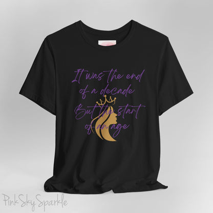 Embrace the excitement of a new era with our End of a Decade, Start of an Age T-shirt, inspired by Taylor Swift's iconic lyrics. Featuring the words It was the end of a decade, But the start of an age in a purple marker script font with a gold silhouette of a woman wearing a crown.