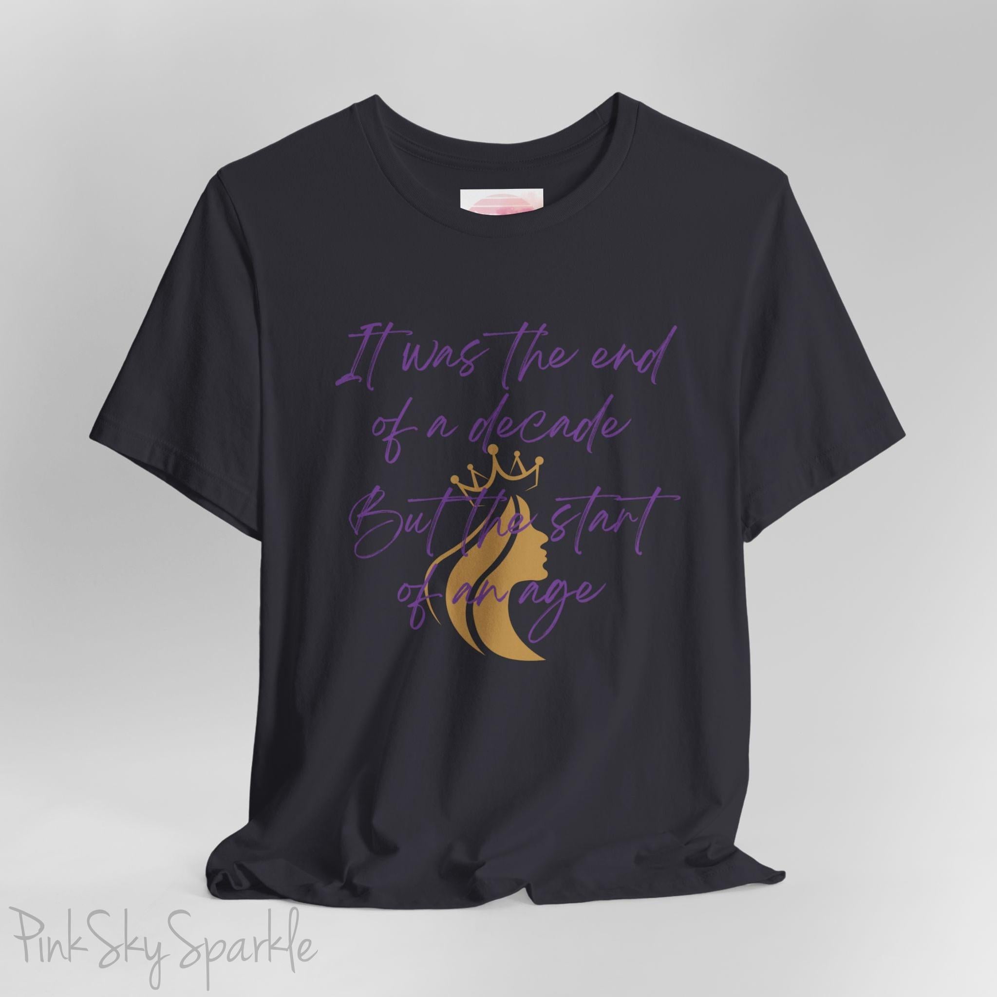 Embrace the excitement of a new era with our End of a Decade, Start of an Age T-shirt, inspired by Taylor Swift's iconic lyrics. Featuring the words It was the end of a decade, But the start of an age in a purple marker script font with a gold silhouette of a woman wearing a crown.