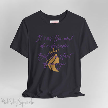Embrace the excitement of a new era with our End of a Decade, Start of an Age T-shirt, inspired by Taylor Swift's iconic lyrics. Featuring the words It was the end of a decade, But the start of an age in a purple marker script font with a gold silhouette of a woman wearing a crown.