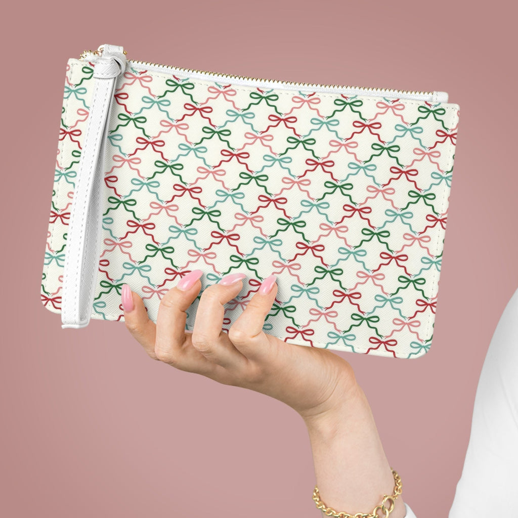 Hand holding a patterned pouch with bows against a pink background
