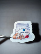 Sticker with jar of flour, loaf of bread and a rose with words "flOUR SONG" on it. 