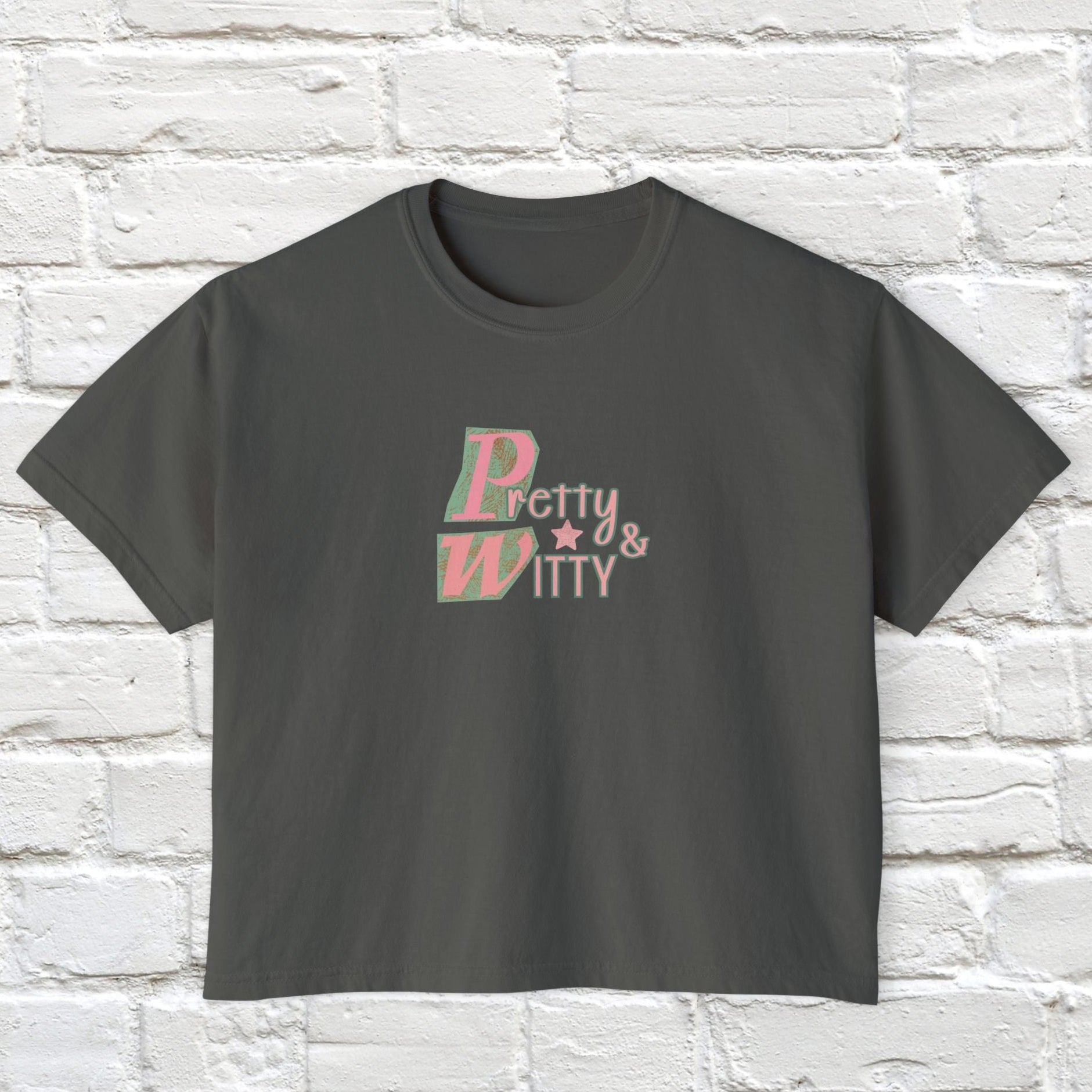 Gray t-shirt with 'Pretty & Witty' text on a white brick wall background
