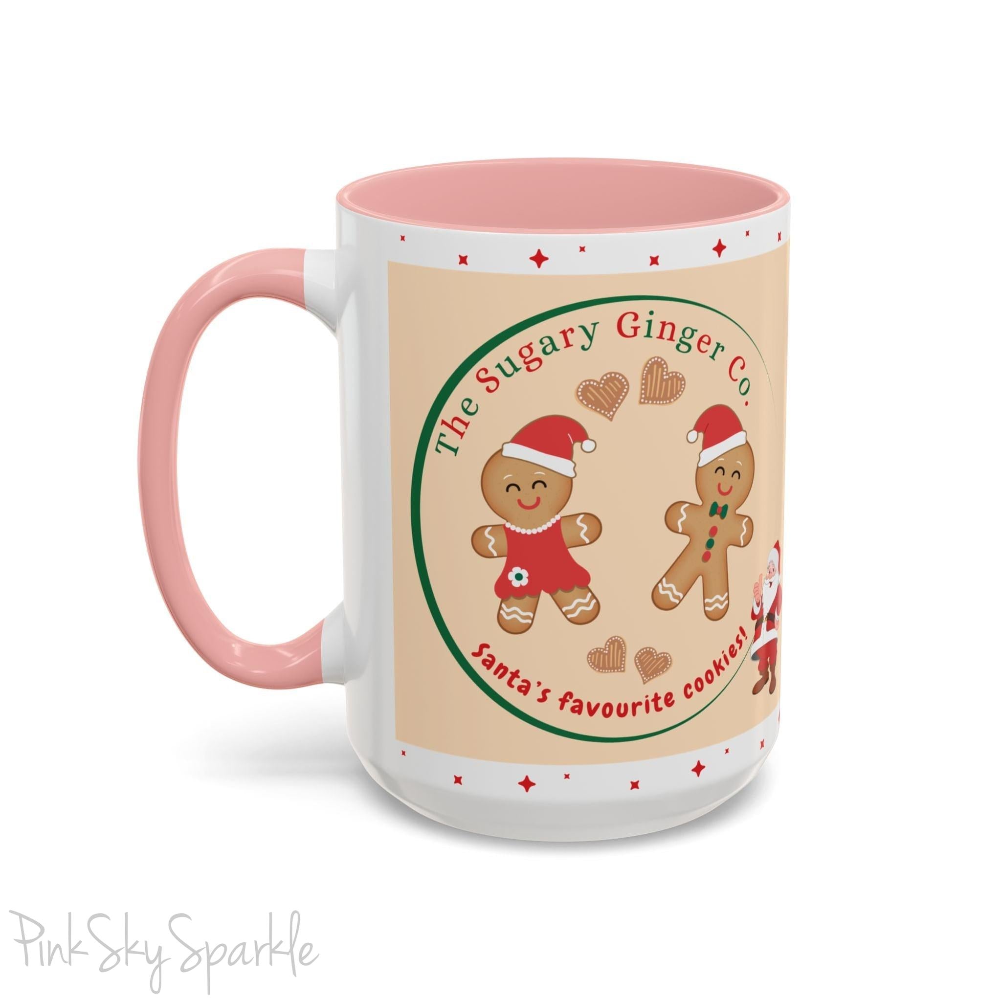 Holiday Gingerbread Coffee Mug featuring a male and female gingerbread cookies next to Santa with giving a thumbs up and the writing The Sugary Ginger Co. written at the top and Santa's favourite cookies at the bottom. The mug has a pink handle and pink interior. 
