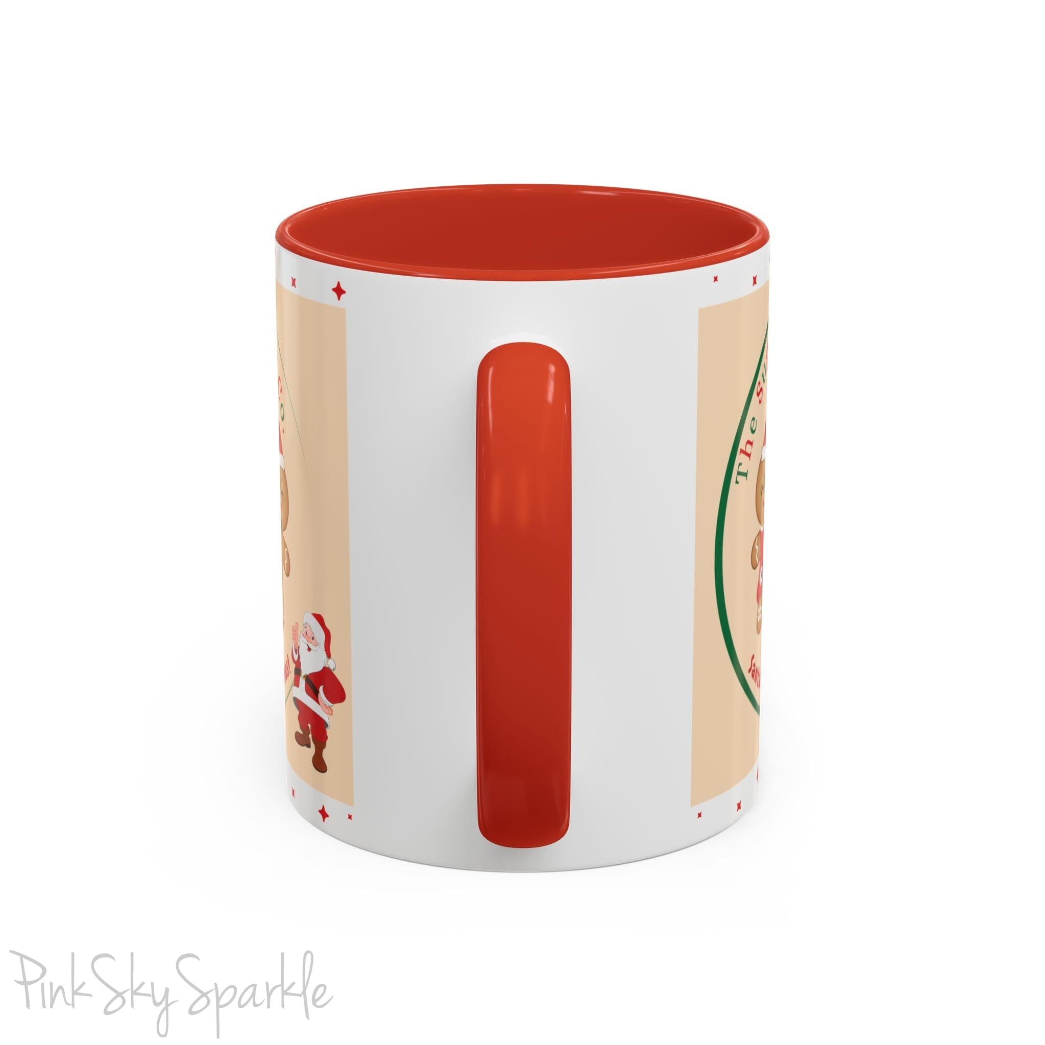Holiday Gingerbread Coffee Mug featuring a male and female gingerbread cookies next to Santa with giving a thumbs up and the writing The Sugary Ginger Co. written at the top and Santa's favourite cookies at the bottom. The mug has a red handle and red interior. 